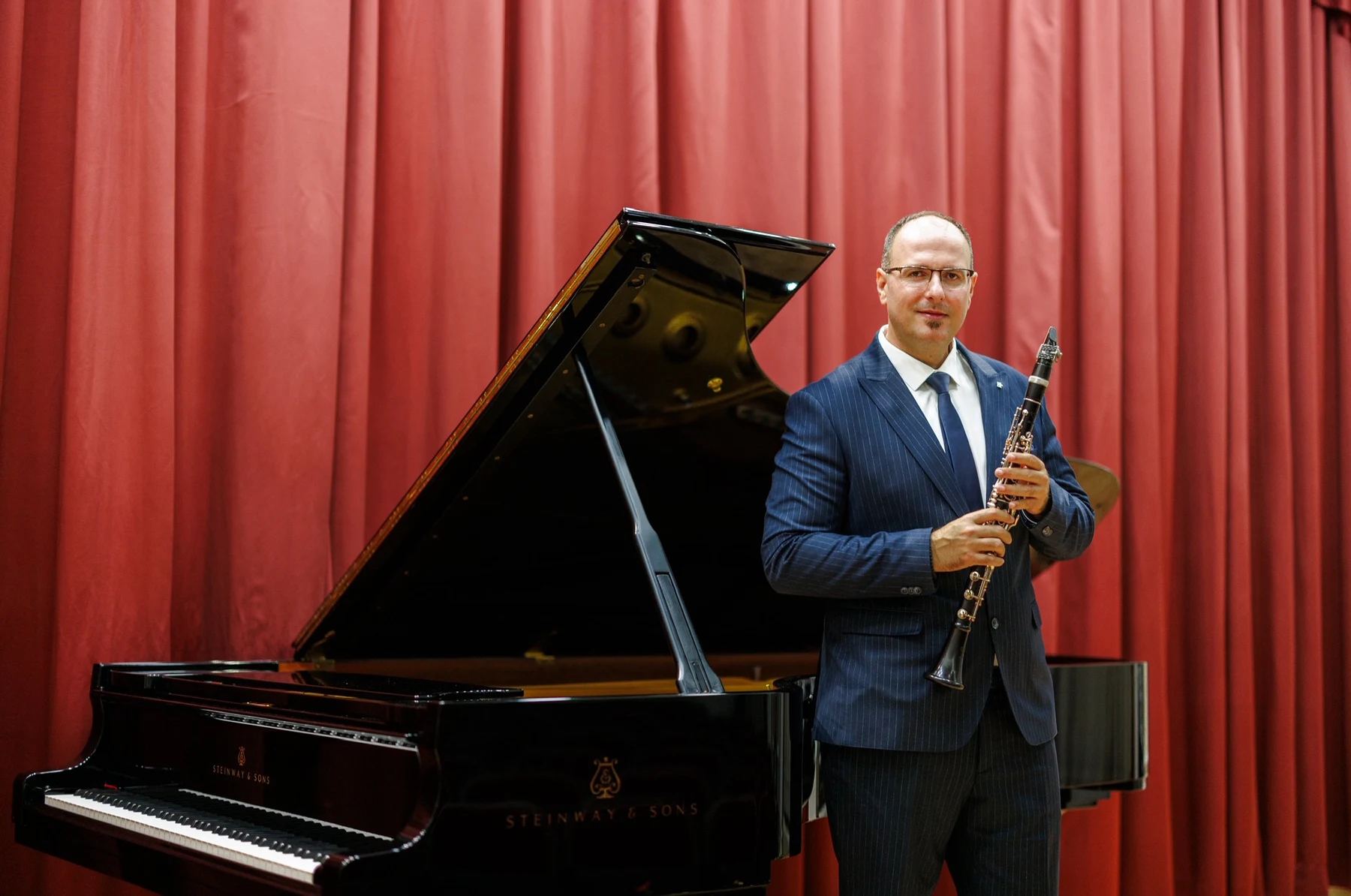 Milos Mijatovic with his clarinet beside a grand piano